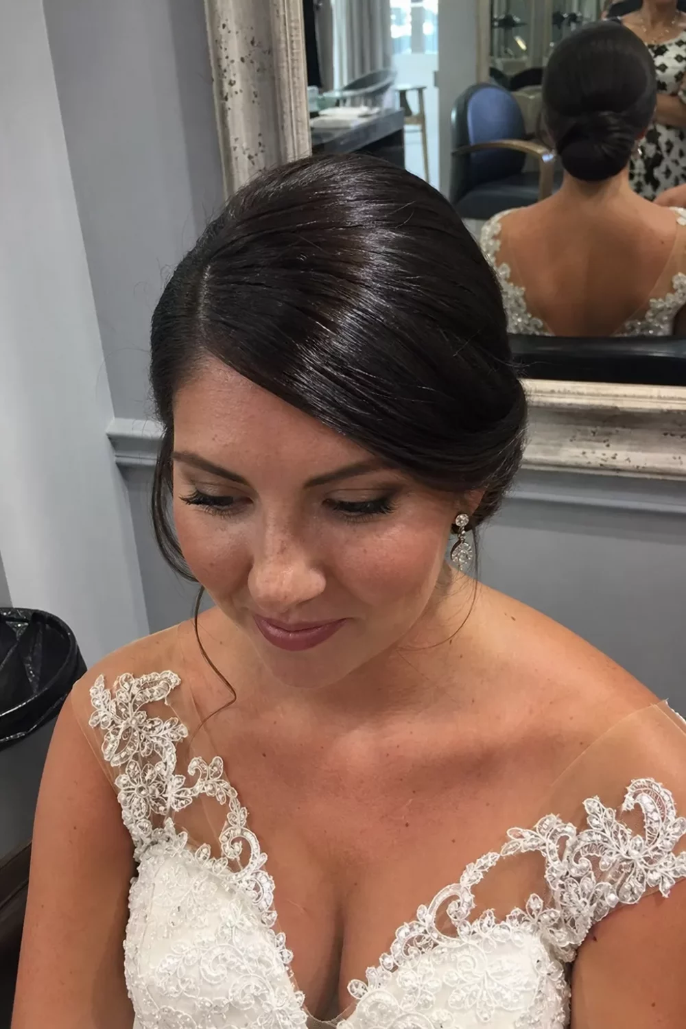 Bride with sleek chignon and deep side part, bridal hair updos front view