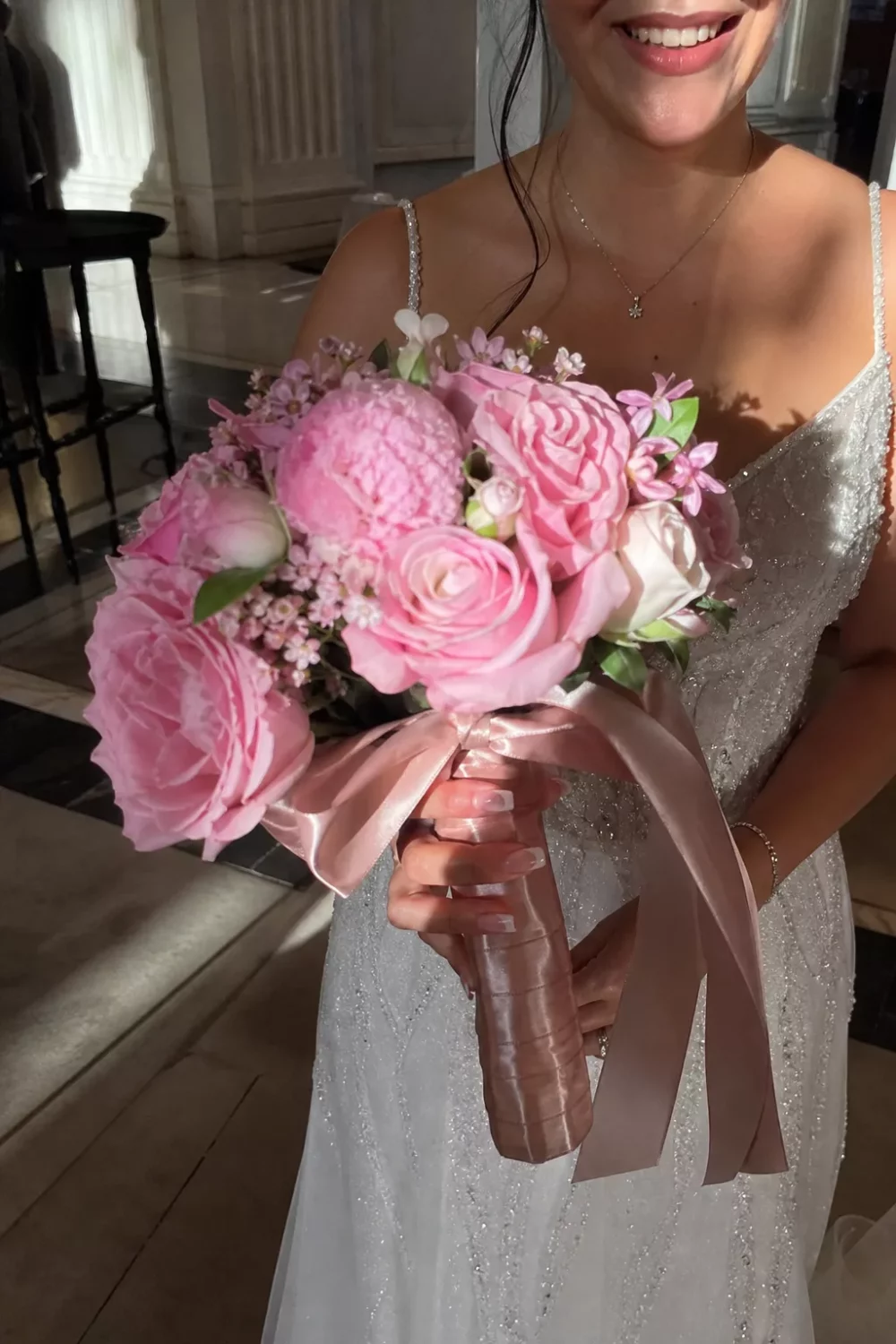 Bride holding pink wedding bouquet with rose gold ribbon wrap detail