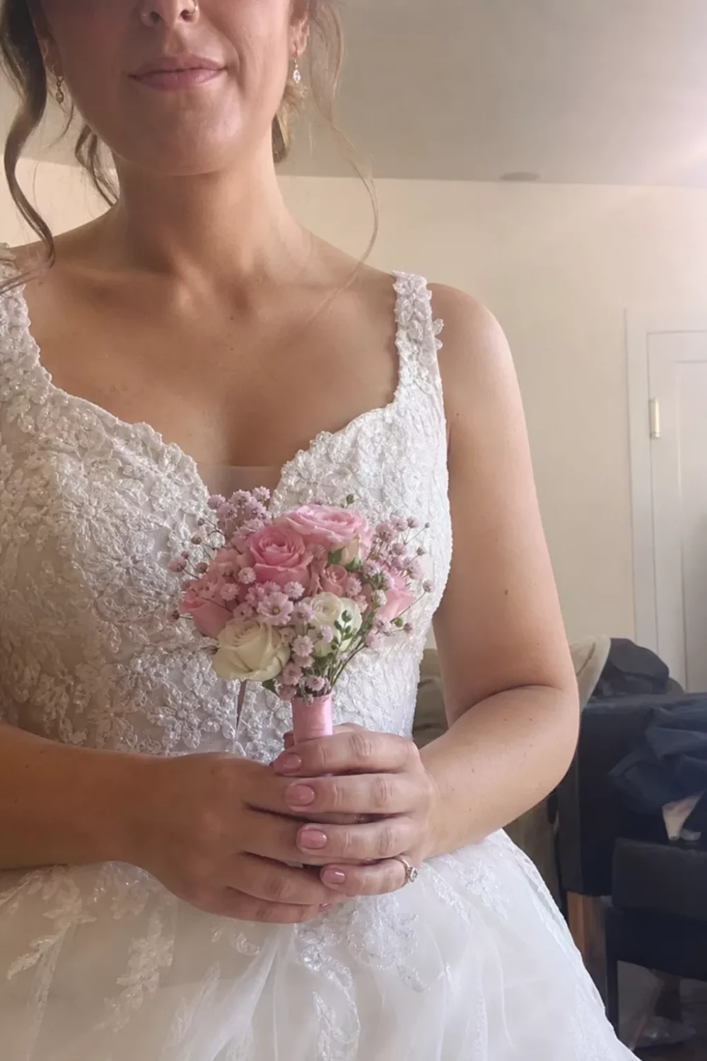 Bride holding a petite pink wedding bouquet with roses and baby's breath