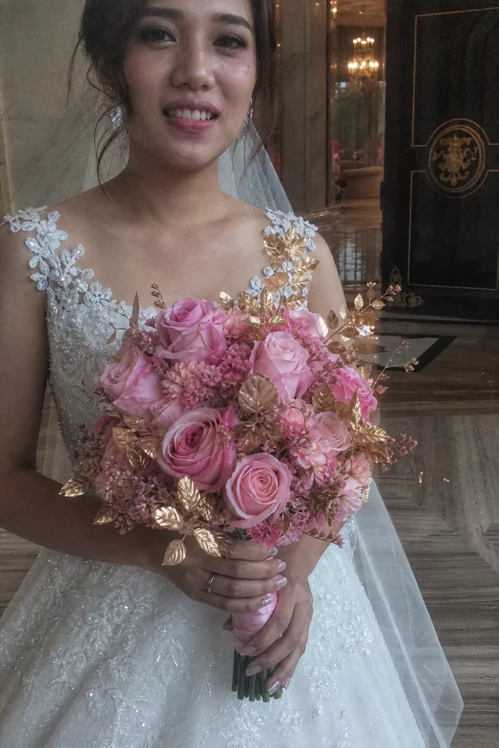 Bride holding pink wedding bouquet with gold leaf foliage accents