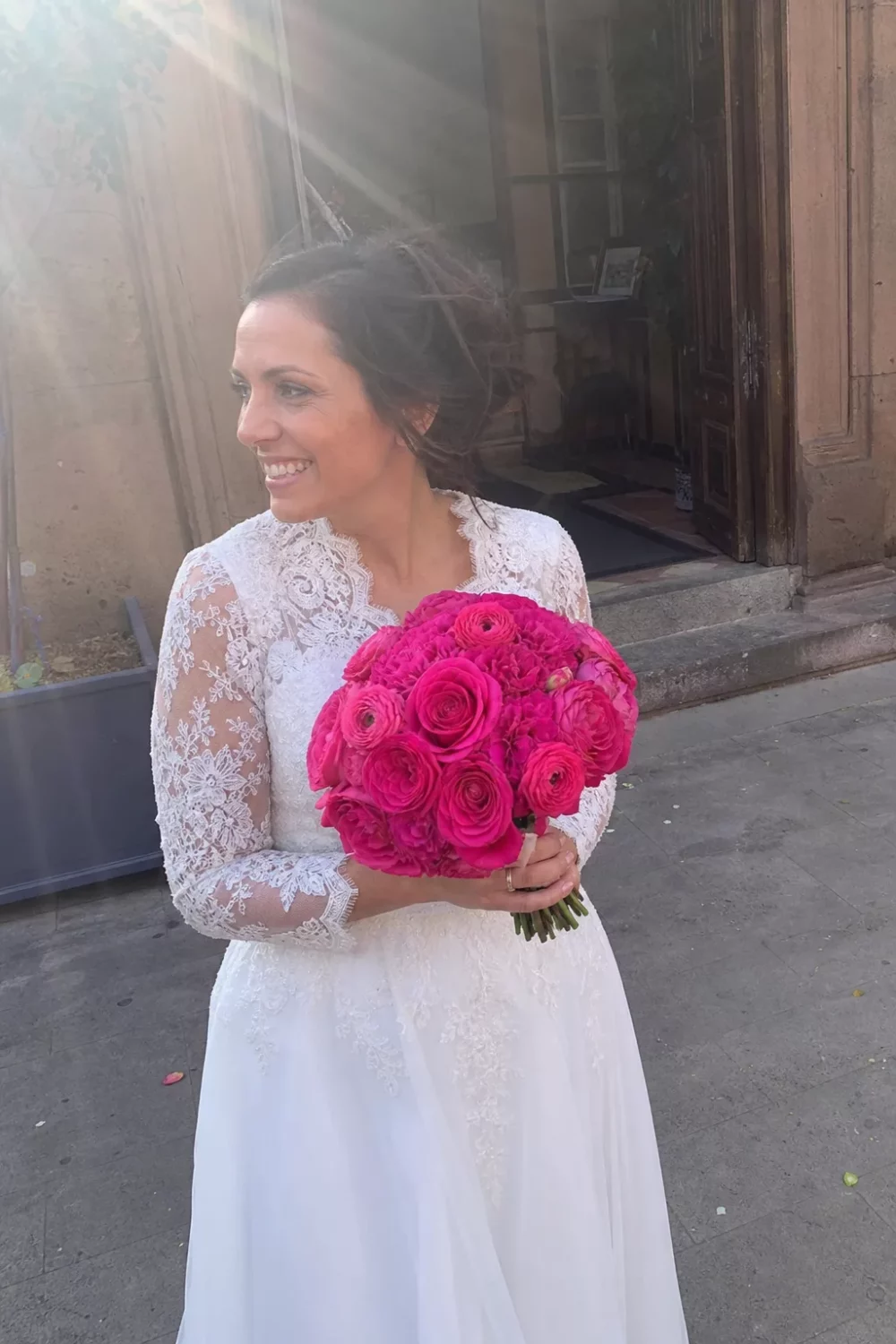 Bride holding a hot pink wedding bouquet of roses and ranunculus outdoors