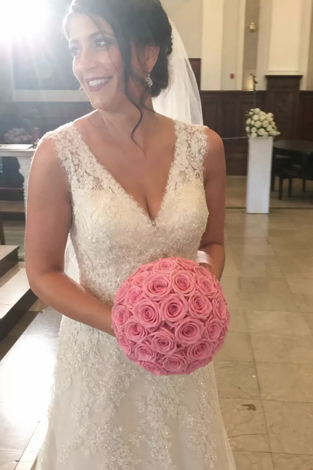 Bride holding a round pink rose ball, one of many pink wedding bouquets ideas