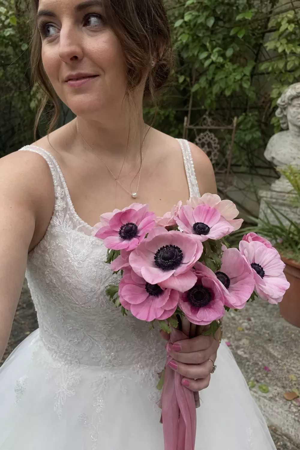 Bride holding a pink wedding bouquet of pink anemones with dark centers