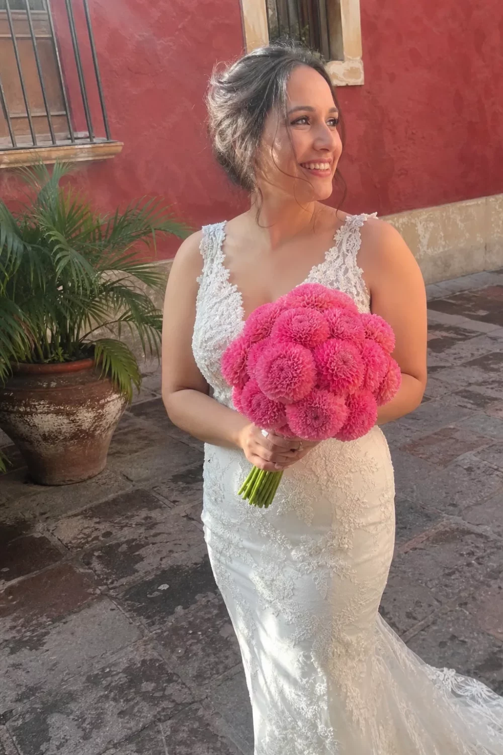 Bride holding a vivid pink pom-pom style pink wedding bouquet outdoors