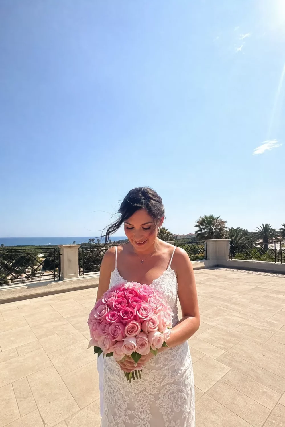 Bride holding a two-tone pink ombre wedding bouquet on a sunny terrace