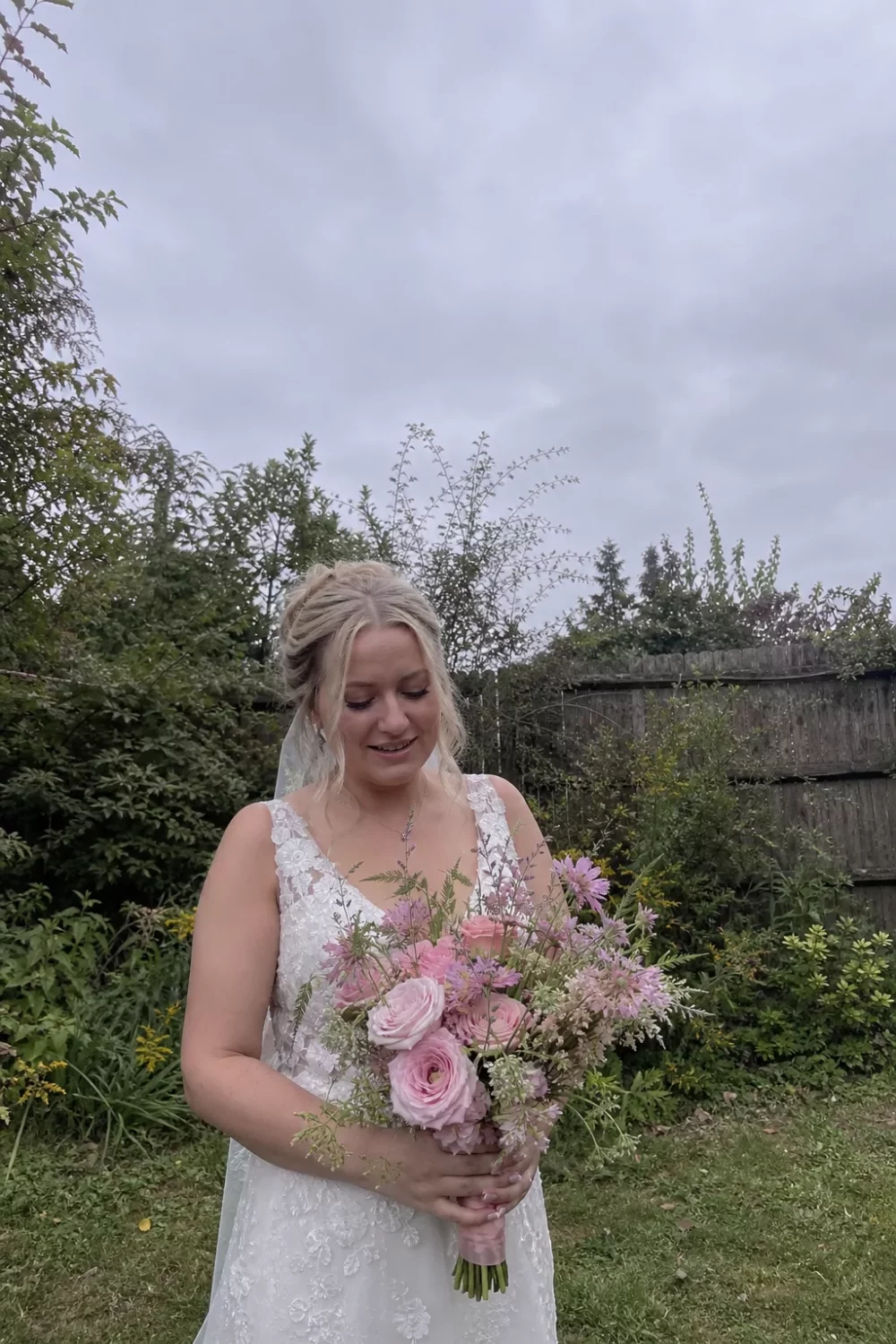 Bride holding a loose pale pink wedding bouquet with garden roses and asters