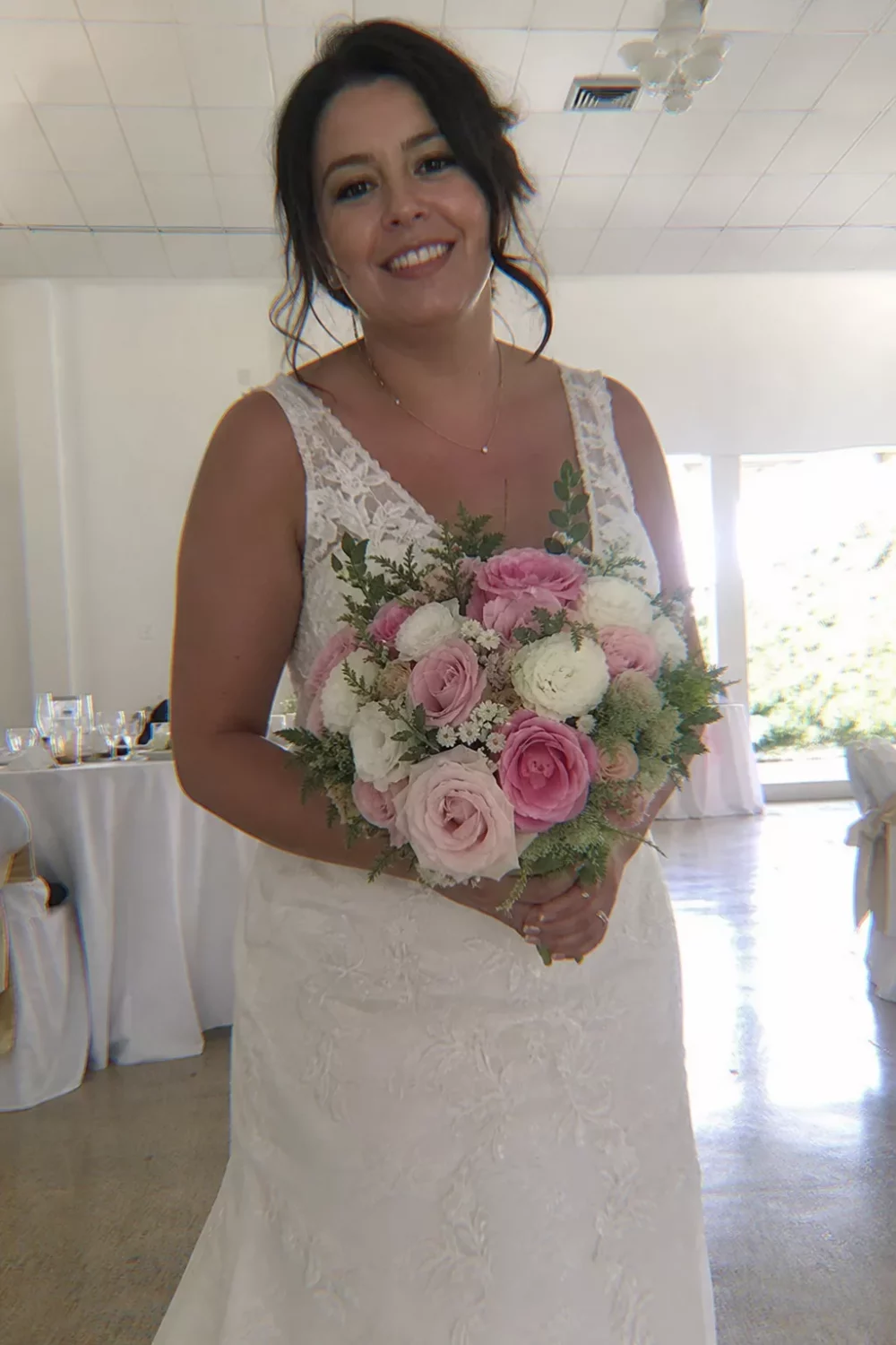 Bride holding a pink wedding bouquet mixed with white flowers and greenery