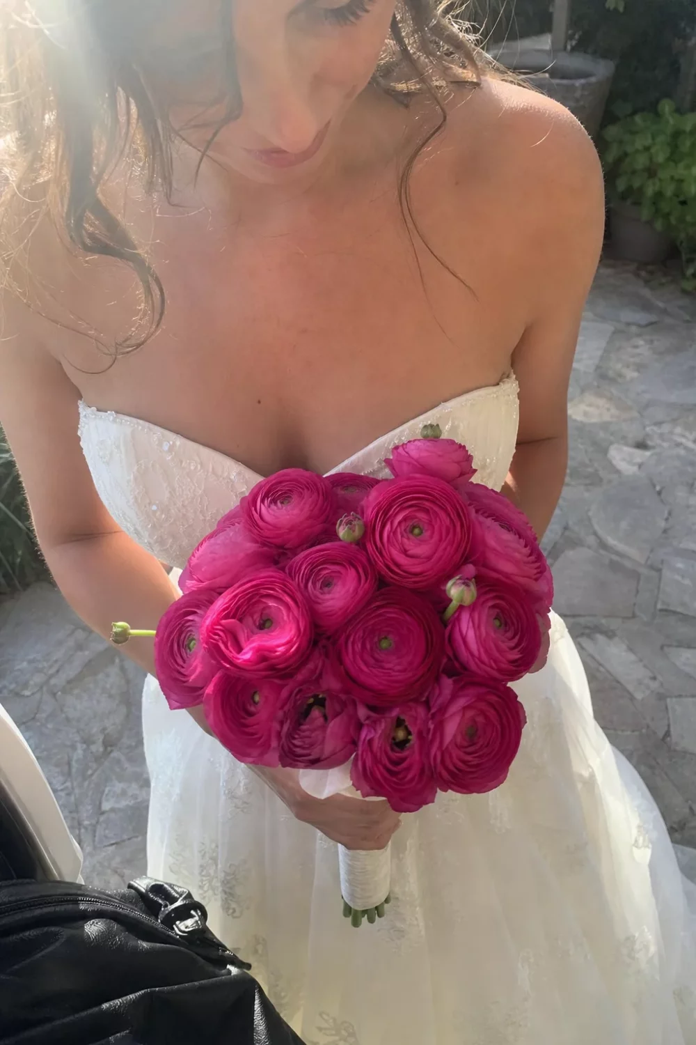 Bride holding deep magenta ranunculus pink wedding bouquet outdoors
